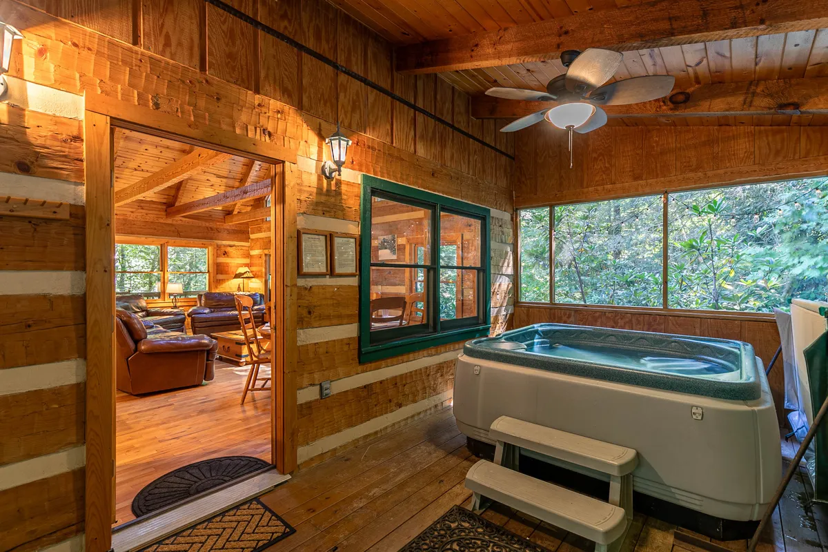An inviting indoor hot tub area with wooden walls and large windows, allowing the outdoors in. The hot tub is the focal point, surrounded by natural views and bathed in soft natural light. The space feels private yet connected to nature, offering a serene spot to soak and relax.